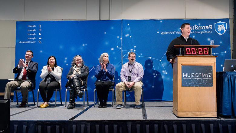 Five Open Innovation Challenge finalists are seated on stage as they wait to present their ideas